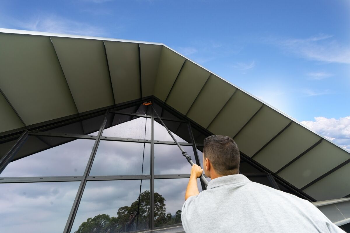 Remarkable team member cleaning upper glazing with a pole