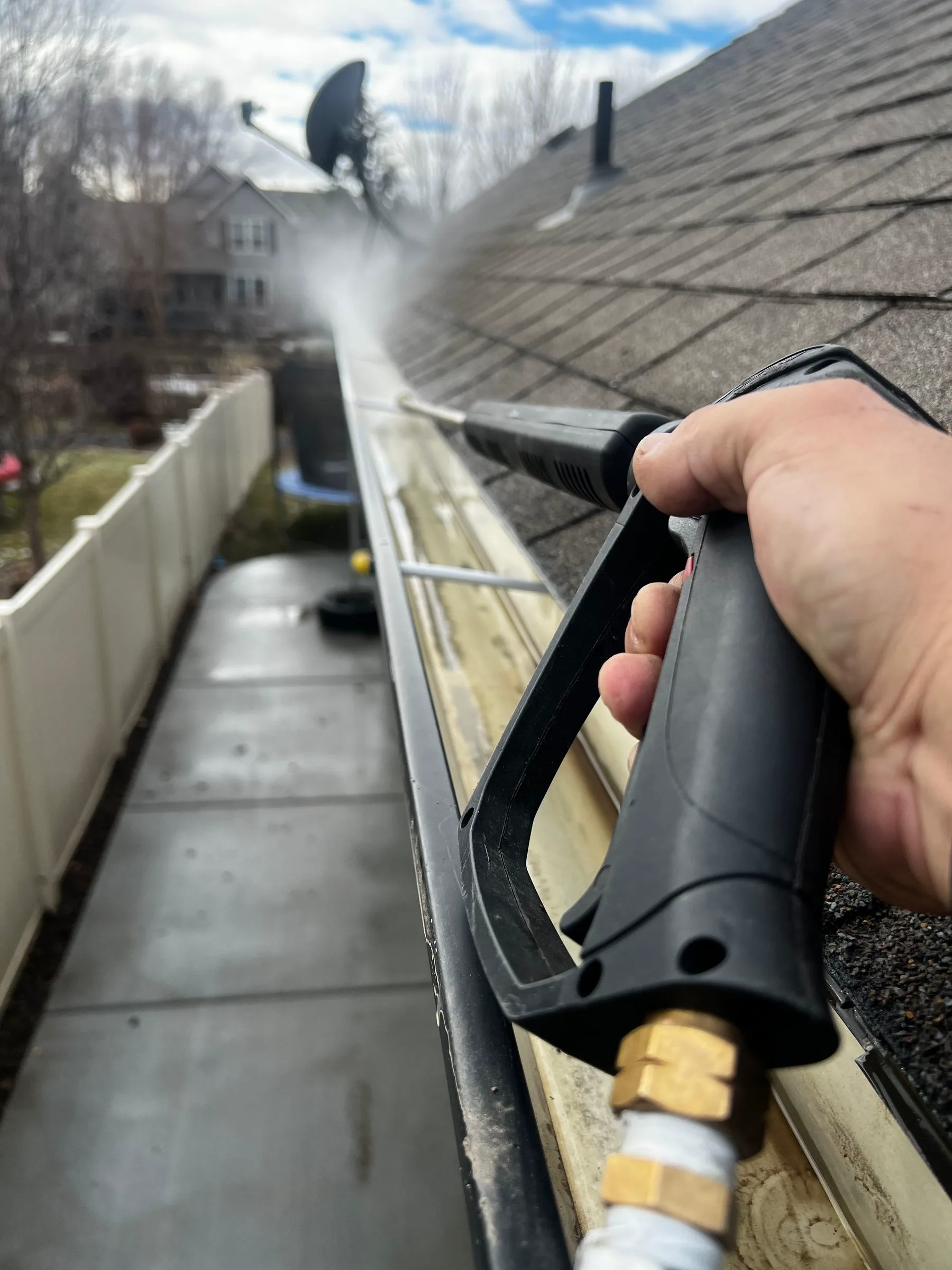 Gutter-cleaning tool removing debris from a low-rise roofline